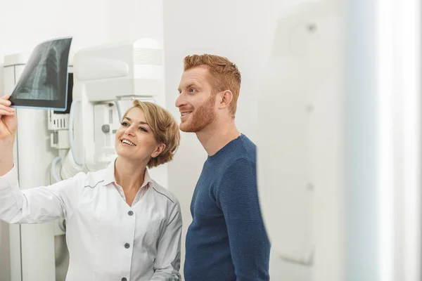 Усміхнений лікар і пацієнт дивиться на рентгенівський знімок — стокове фото