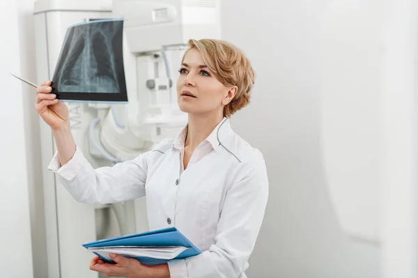 Цікава жінка-лікар, що тримає рентгенографію — стокове фото