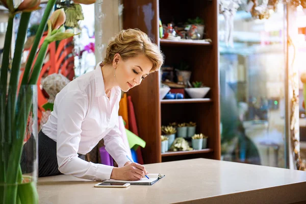 Professional female florist making notes — Stock Photo, Image
