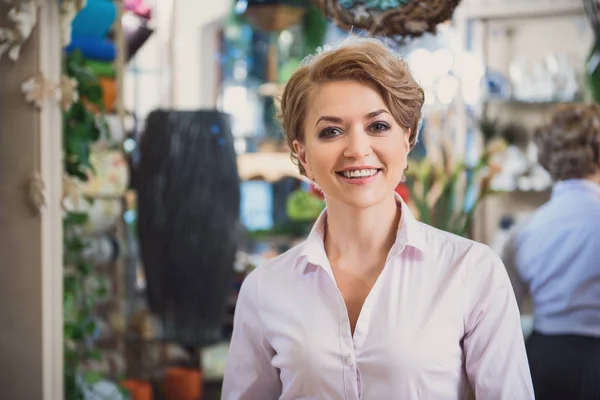 Щаслива жінка насолоджується роботою в магазині — стокове фото