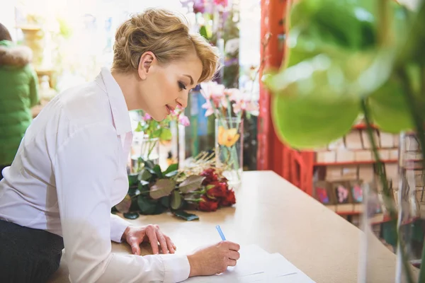 お花屋さんでノートを作る陽気な女性 — ストック写真