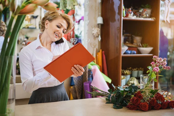 Skillful flower shop assistant communicating by telephone — Stock Photo, Image