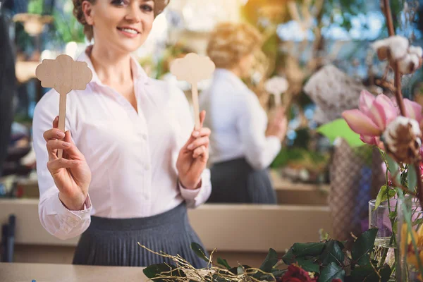 Vrolijke vrouwelijke bloemist houten figuren te houden — Stockfoto