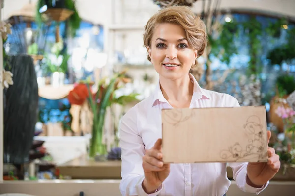 Joyeux propriétaire de magasin de fleurs présentant des marchandises — Photo