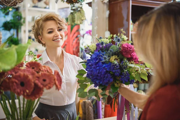 Mulher alegre dando flores para senhora — Fotografia de Stock