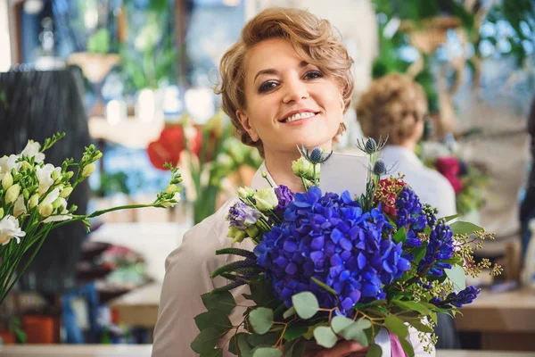 Joyeuse femme portant des fleurs dans la boutique — Photo