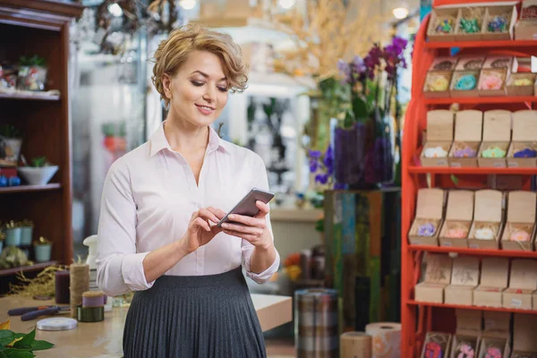 Joyful florista femenina usando el teléfono móvil — Foto de Stock