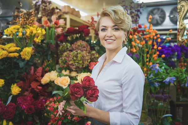 Mulher amigável com buquê na loja de flores — Fotografia de Stock
