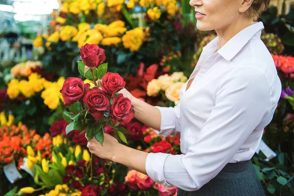 Весела жінка-флорист тримає елегантні квіти — стокове фото