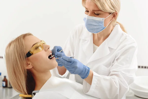 Dentista cuidando da cavidade oral feminina — Fotografia de Stock