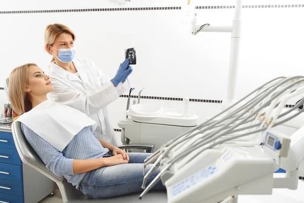 Estomatologista apontando conjunto de cavidades na radiografia — Fotografia de Stock