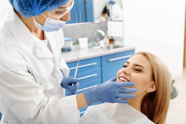 Tandläkare kontrollera munhålan av klienten efter behandling av tänder — Stockfoto
