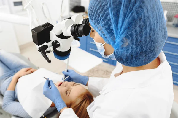 Dentist watching in surgical equipment to fill tooth — Stock Photo, Image