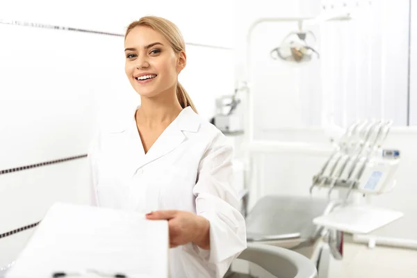 Estomatologista dando espaço em branco para seu cliente no escritório — Fotografia de Stock