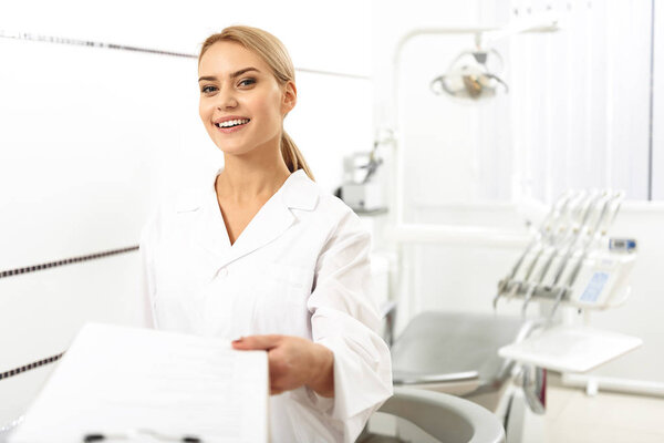 Stomatologist giving blank to her client in office