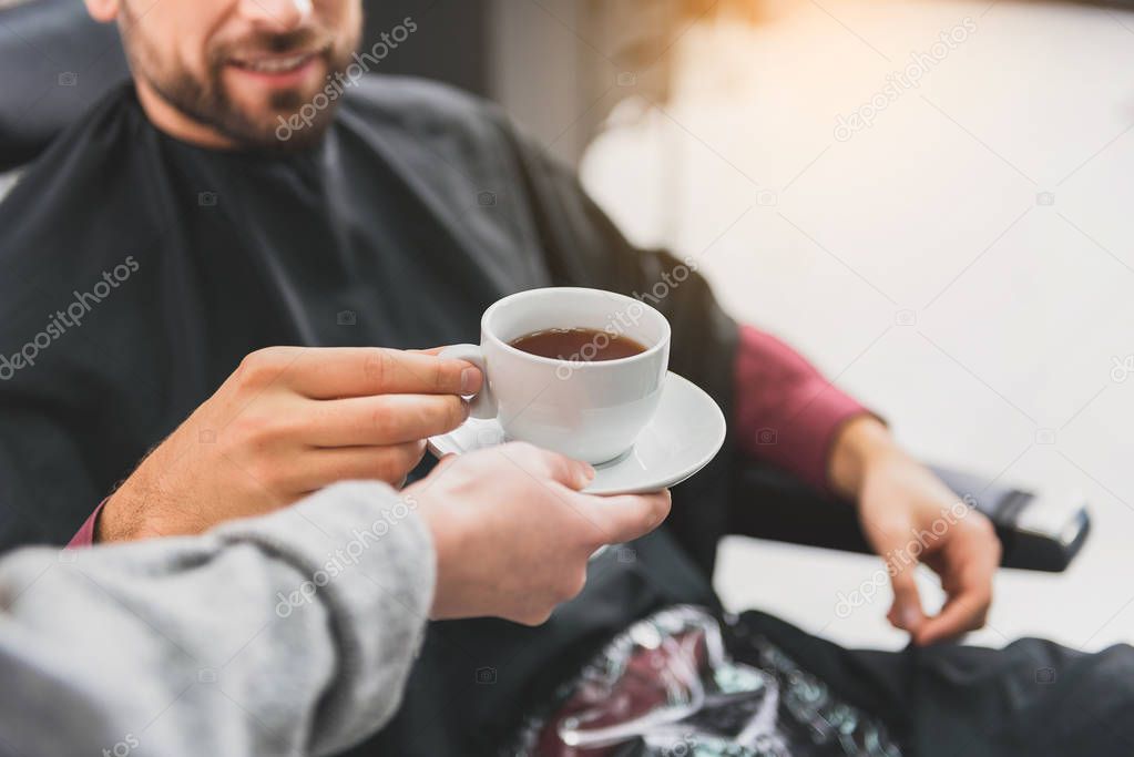 Hairdresser treating her customer with hot beverage