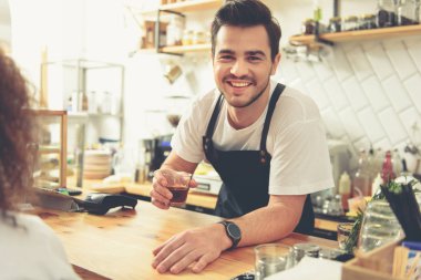 Gülümseyen adam ziyaretçiye içecek bir vererek