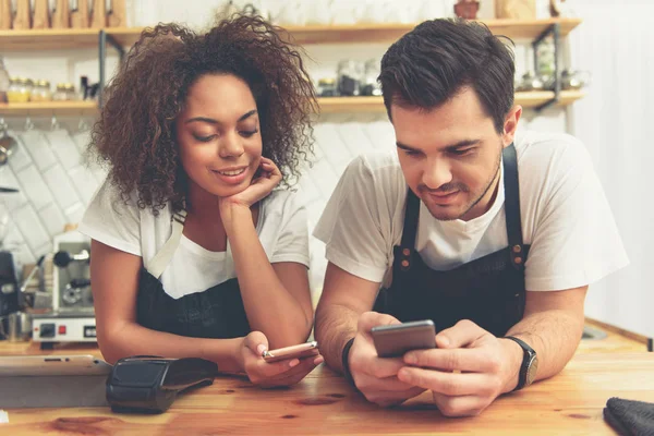 Alegre baristas mirando sus teléfonos — Foto de Stock