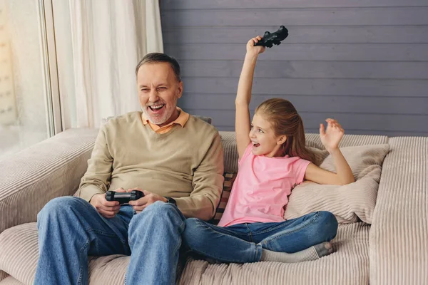 Joyeux vieil homme et petite-fille divertissant avec des joysticks — Photo