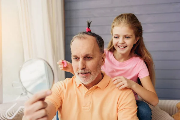 Menina alegre fazendo penteado para o avô — Fotografia de Stock