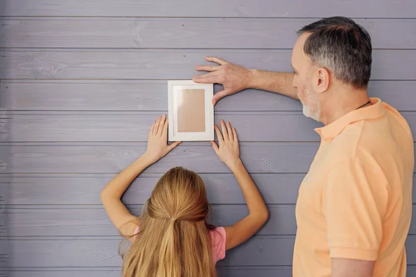 Neta e avós ajustando o quadro de família — Fotografia de Stock