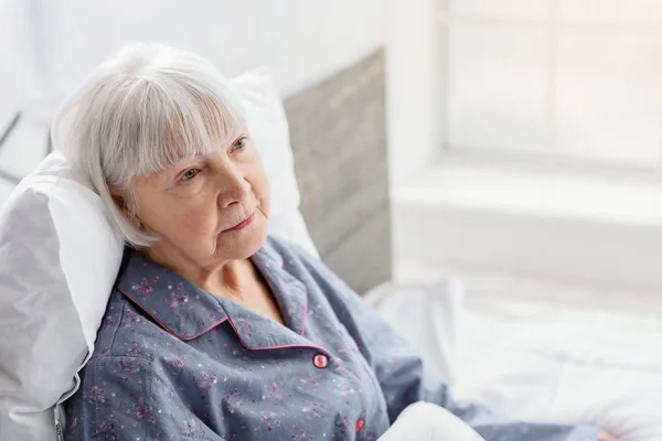 Женщина-пенсионер лежит в светлой квартире клиники — стоковое фото
