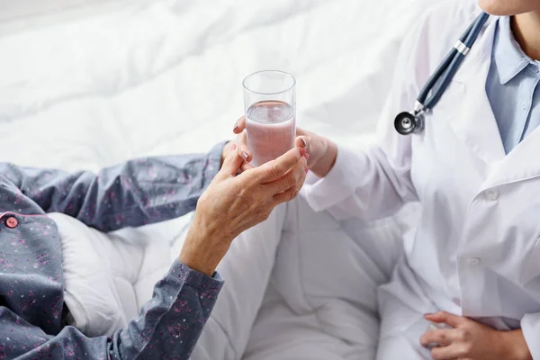 Terapéutica que sostiene la bebida al paciente en la clínica — Foto de Stock