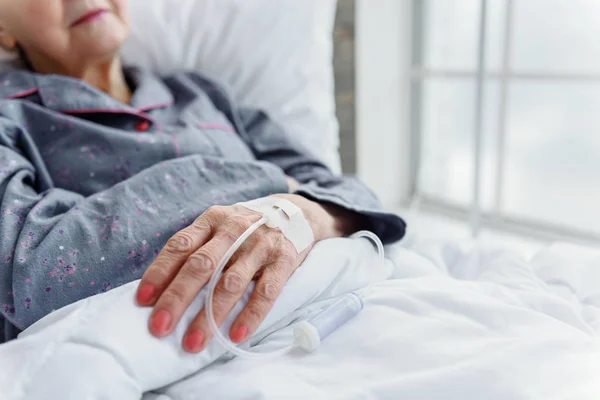 Senior lady is on drip bulb reclining in cot — Stock Photo, Image