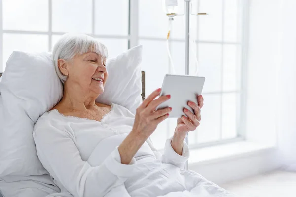 Smiling retiree looking at digital tablet in clinic