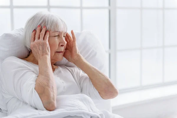Mulher idosa preocupada tem dor de cabeça no hospital — Fotografia de Stock