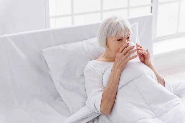 Großmutter probiert Becher mit köstlichem Getränk — Stockfoto