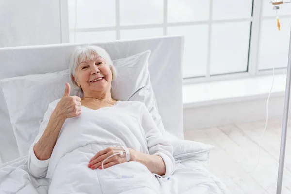 Cheerful old woman is on drop glass in clinic — Stock Photo, Image