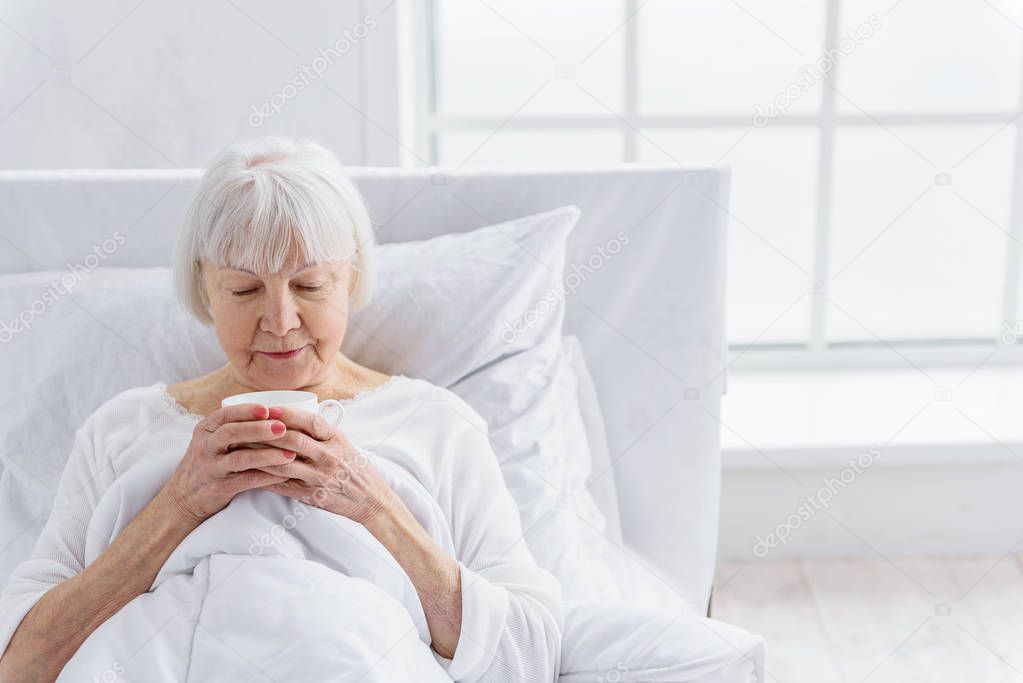 Pleased pensioner delighting cup of tea