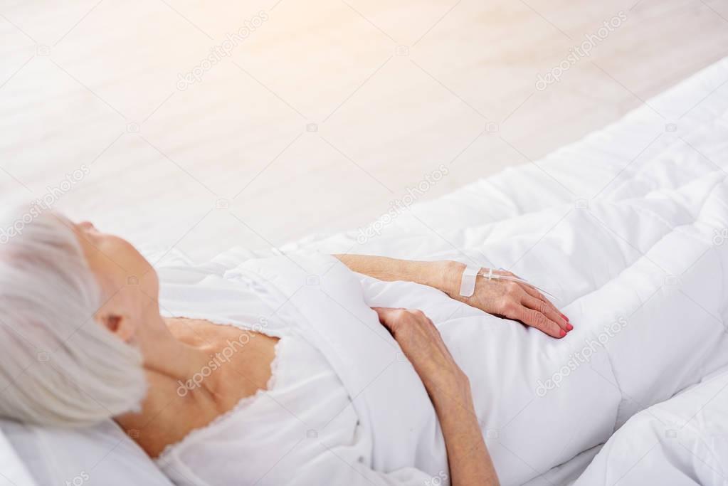 Retiree is on drop glass reclining in bed