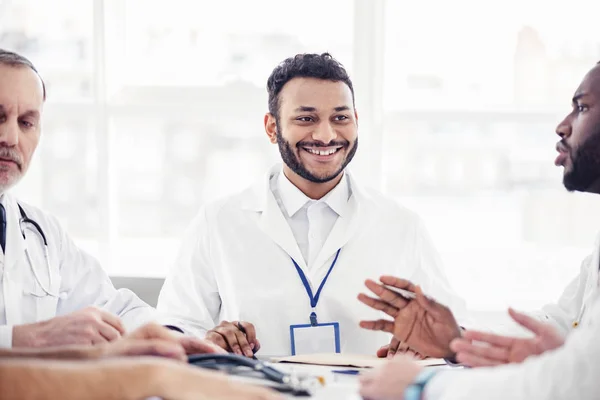Χαμογελώντας γιατρός ακούει τους συναδέλφους του σε συνεδρίαση — Φωτογραφία Αρχείου