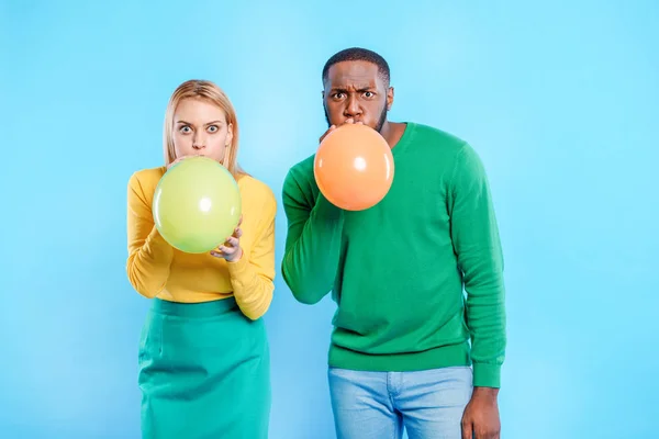 Веселий чоловік і жінка надувають різнокольорові кульки — стокове фото