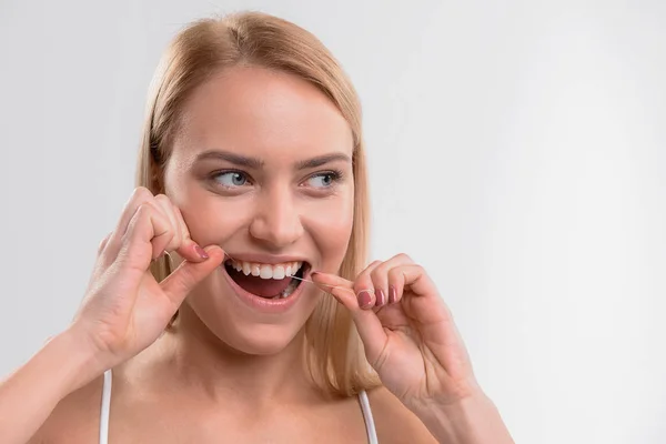 Fröhliche junge Frau mit Zahnseide — Stockfoto