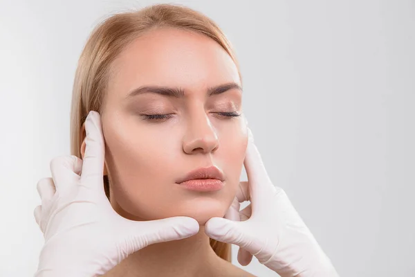 젊은 여자의 얼굴을 검사 하는 외과 의사 — 스톡 사진