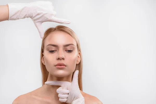 Cirurgião examinando proporção facial de mulher jovem — Fotografia de Stock