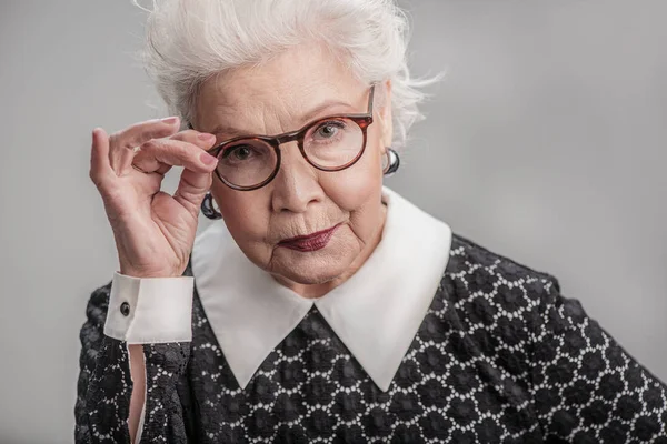 Mulher adulta elegante olhando de cima de seus óculos — Fotografia de Stock