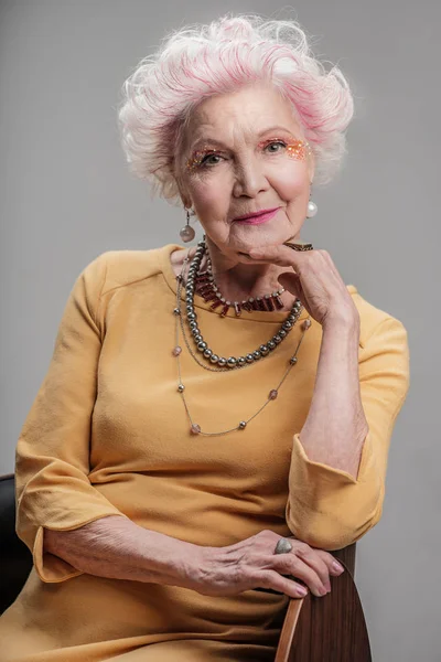 Senior senhora com maquiagem brilhante sentado na cadeira — Fotografia de Stock