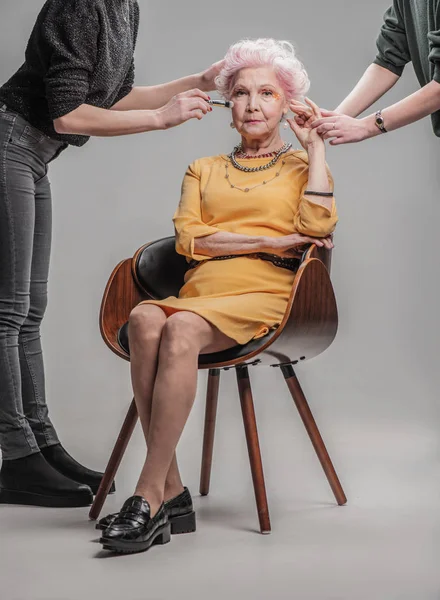 モダンな老婦人 studio で木製の椅子に座って — ストック写真