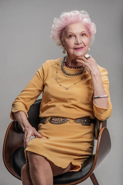 Smiling elderly woman sitting on chair — Stock Photo, Image