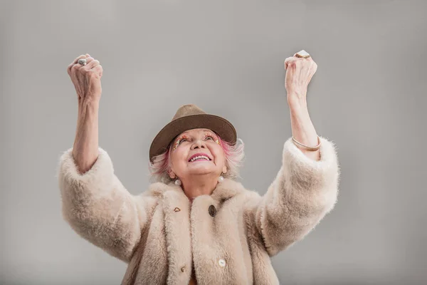 Красивая старшая женщина в коричневой шляпе выражает позитивные эмоции — стоковое фото