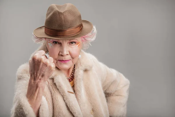 Mürrische Seniorin mit Hut blickt in die Kamera — Stockfoto