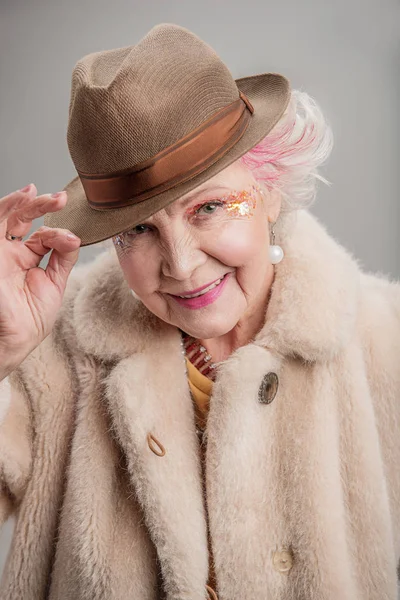 Positive old woman holding her hat by hand — Stock Photo, Image