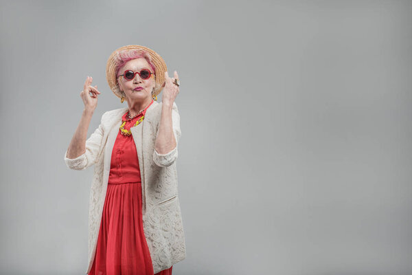 Cheerful aged woman in sunglasses enjoying music