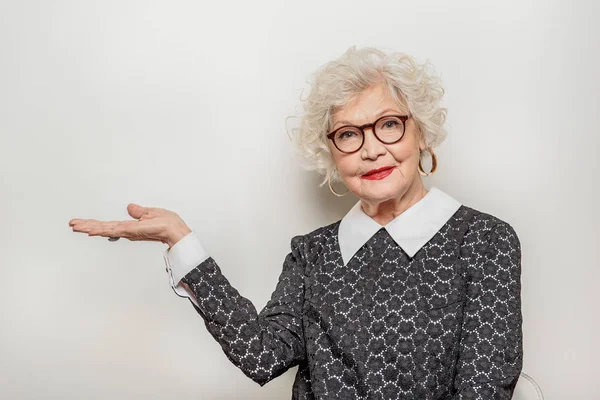 Joyful senior lady showing something by her arm — Stock Photo, Image