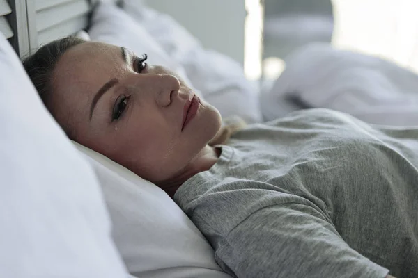 Piangendo donna sdraiata in camera da letto — Foto Stock