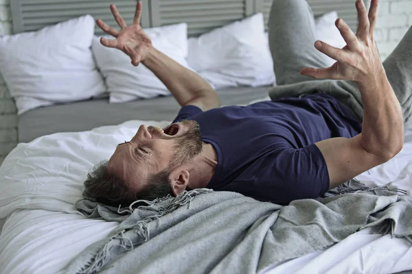 Депрессивный плачущий мужчина в постели — стоковое фото
